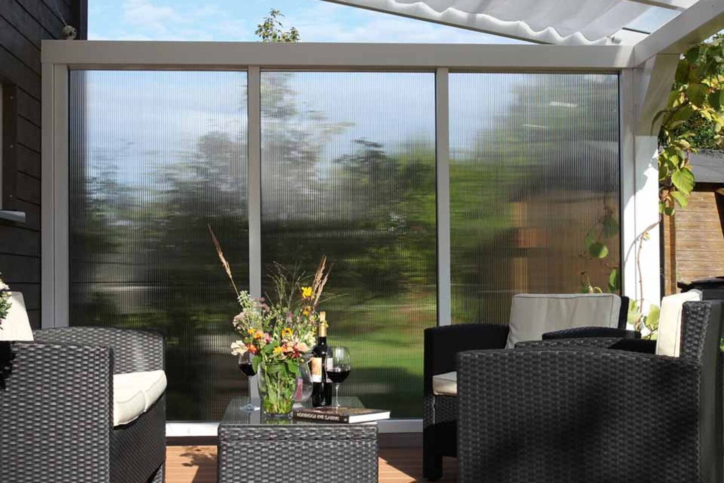 Eine Terrassenüberdachung mit Seitenwand und Sonnensegel von Skan Holz