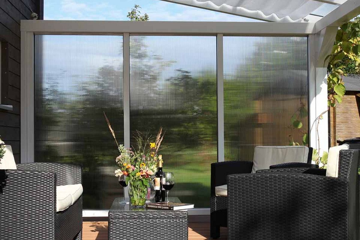 Eine Terrassenüberdachung mit Seitenwand und Sonnensegel von Skan Holz