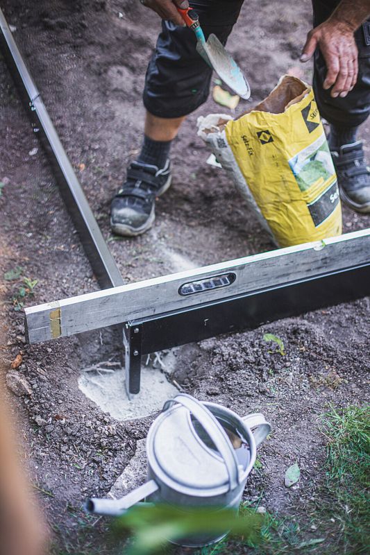 Die Löcher für das Fundament werden mit Schnellbeton ausgefüllt