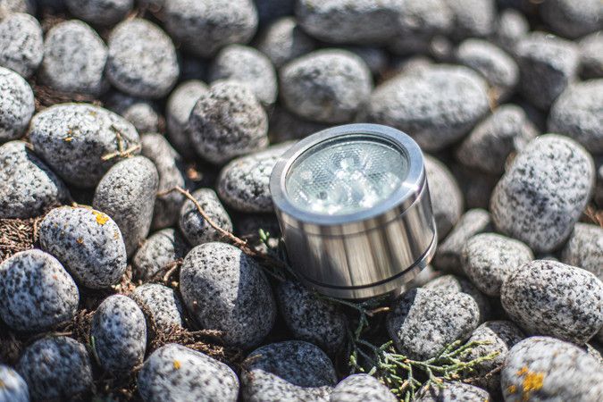 Ein kleiner LED-Strahler im Edelstahllook, der zwischen den Kieselsteinen kaum auffällt